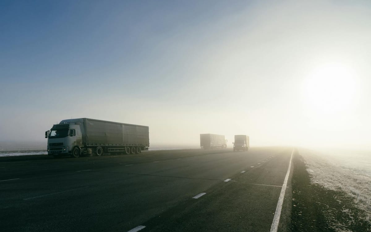 Freight trucks on an open highway at sunrise — the road-haulage layer linking Greater Bay Area factories to Hong Kong's ports and a cross-border trading supply chain