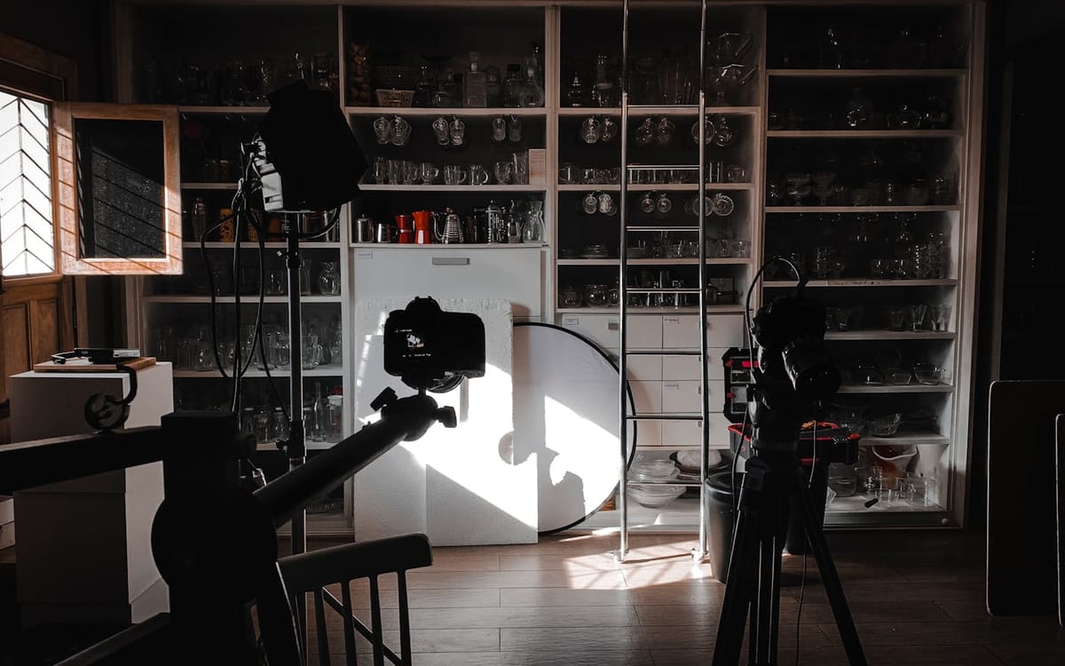 A home filming studio with a camera on a tripod, softbox lights and a reflector set up for a shoot — the production side of a content business that a company structure sits behind