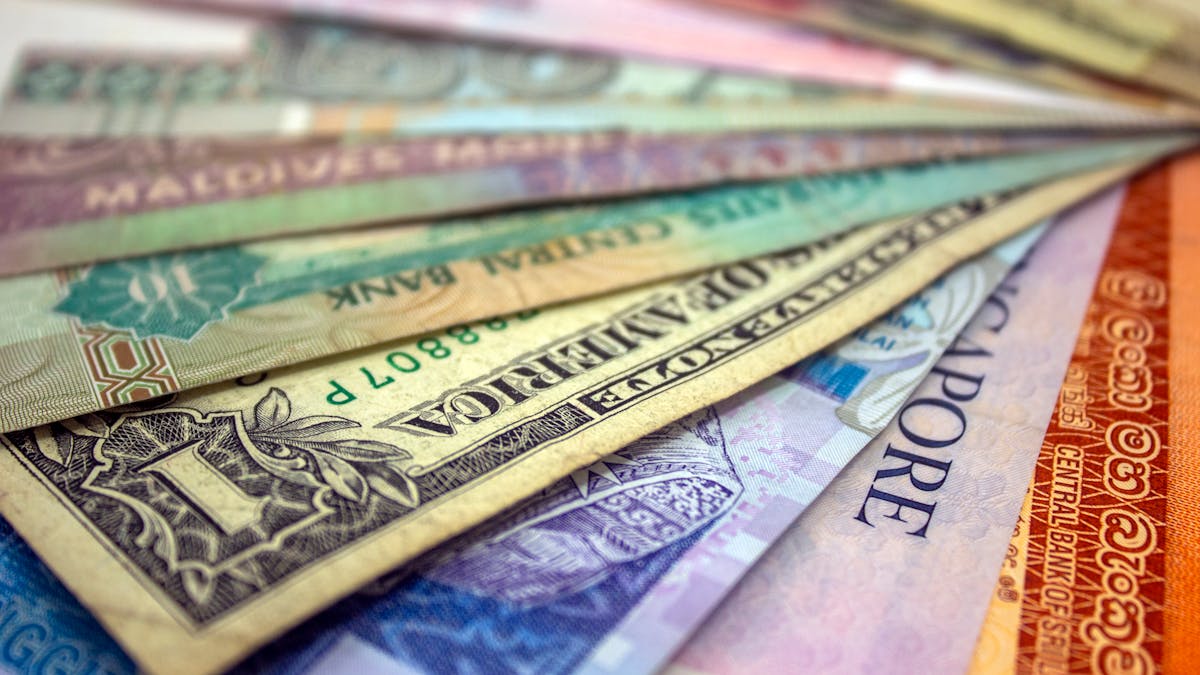 Banknotes from several countries fanned out together on a desk — the multi-currency income an expat-run Hong Kong company handles