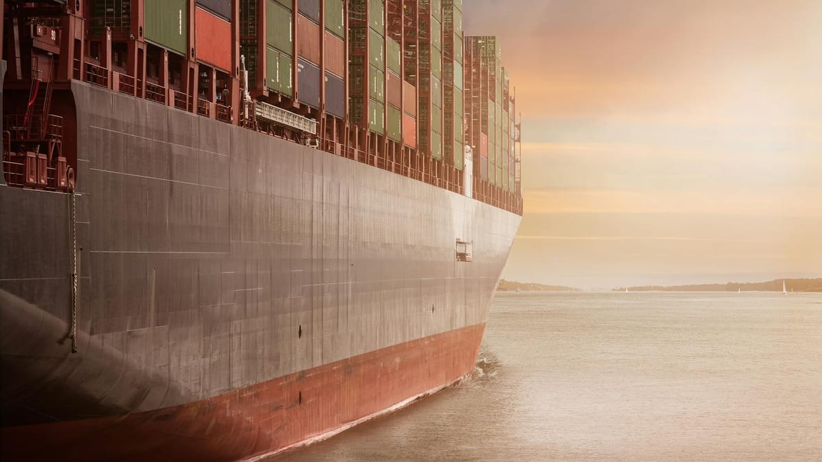 A fully laden container ship at sunset on open water, its hull and stacked containers filling the frame — the physical-goods trade that a Letter of Credit underwrites